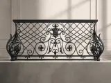 Klasyczna balustrada kuta o historycznym wzornictwie z kartuszem centralnym i ozdobnymi wolutami bocznymi na jasnym tle